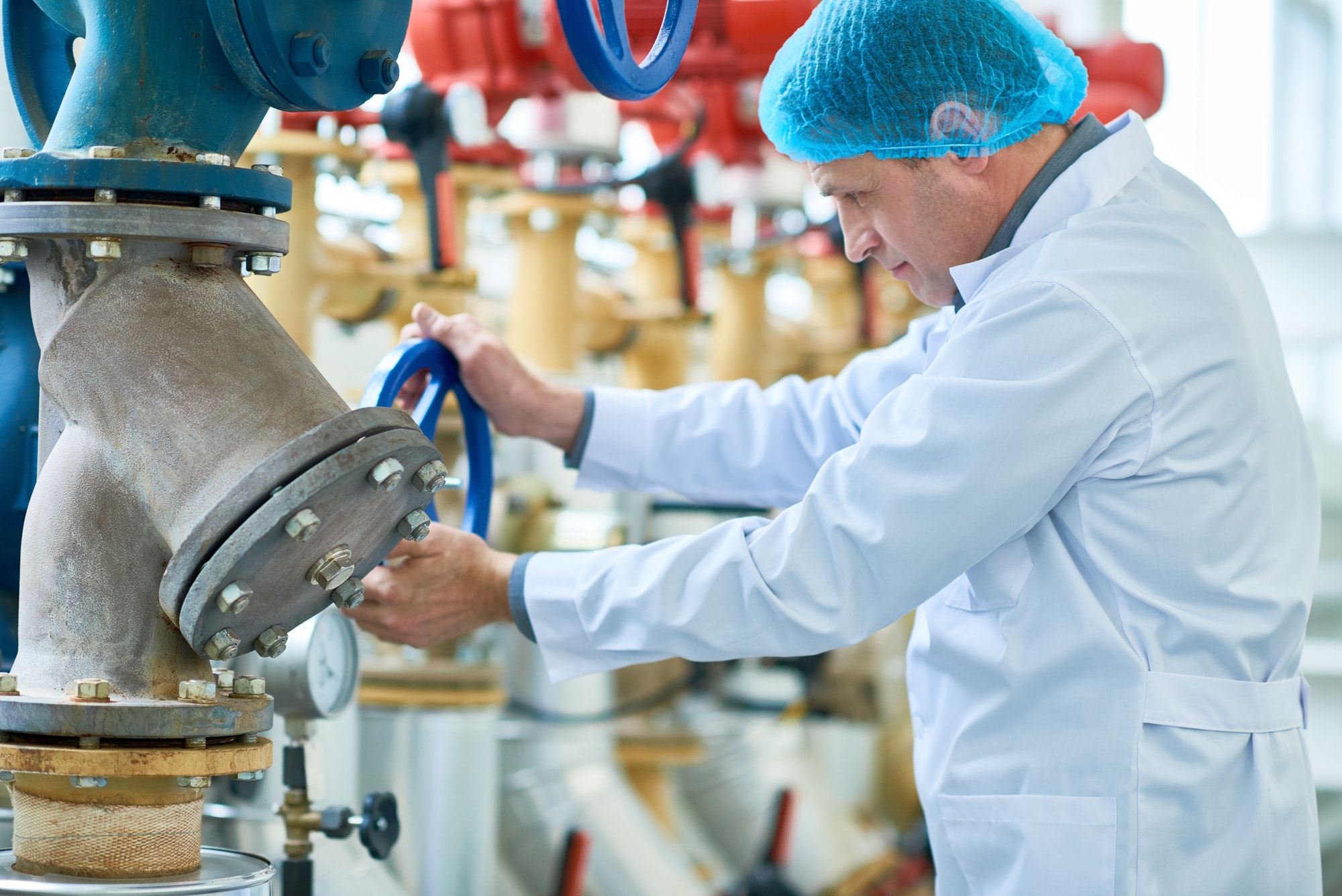 Mature Worker Checking Pipes in Modern Factory